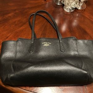 A blackjack Gucci purse with pebble leather and wide straps. Gold branding on it